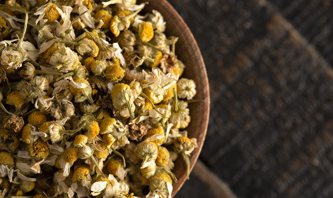 Bowl of Dried Chamomile Flowers on a Wooden Table