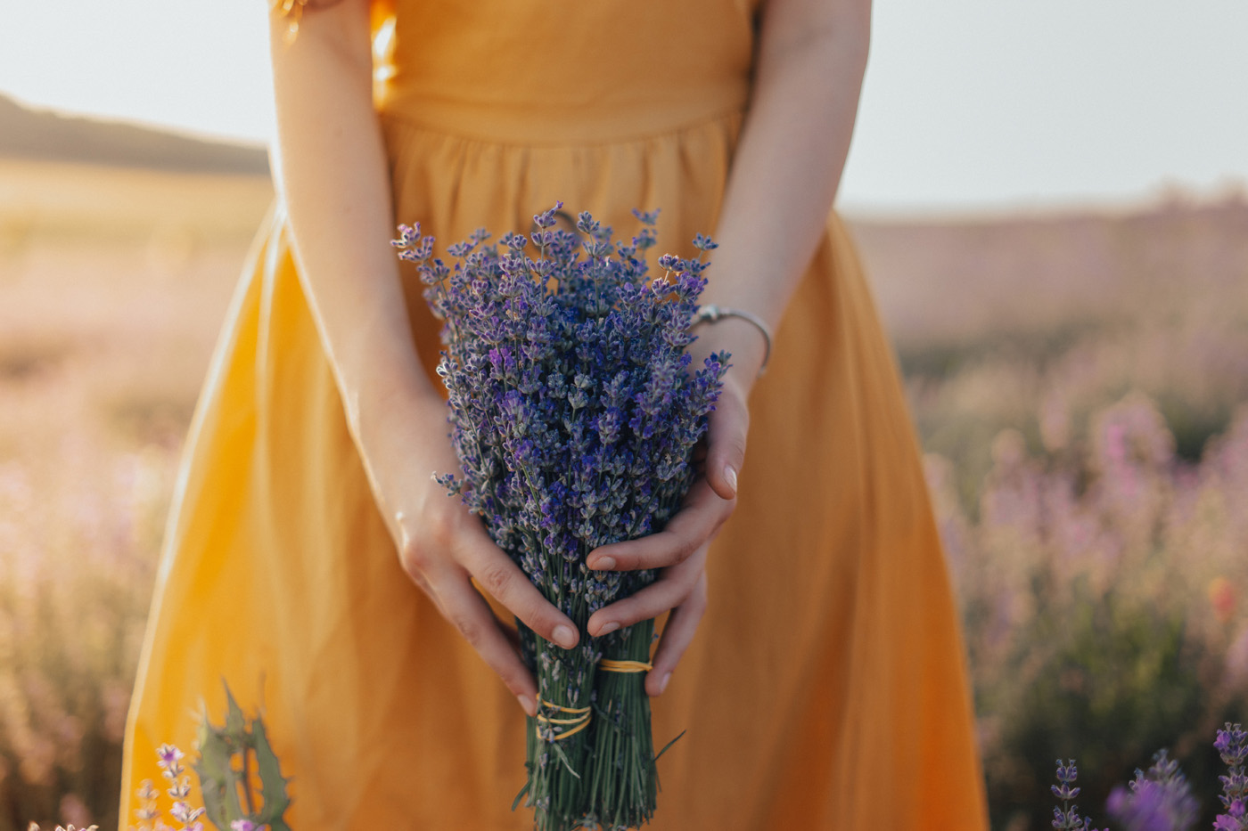 person in yellow dress holding purple lavender bunch