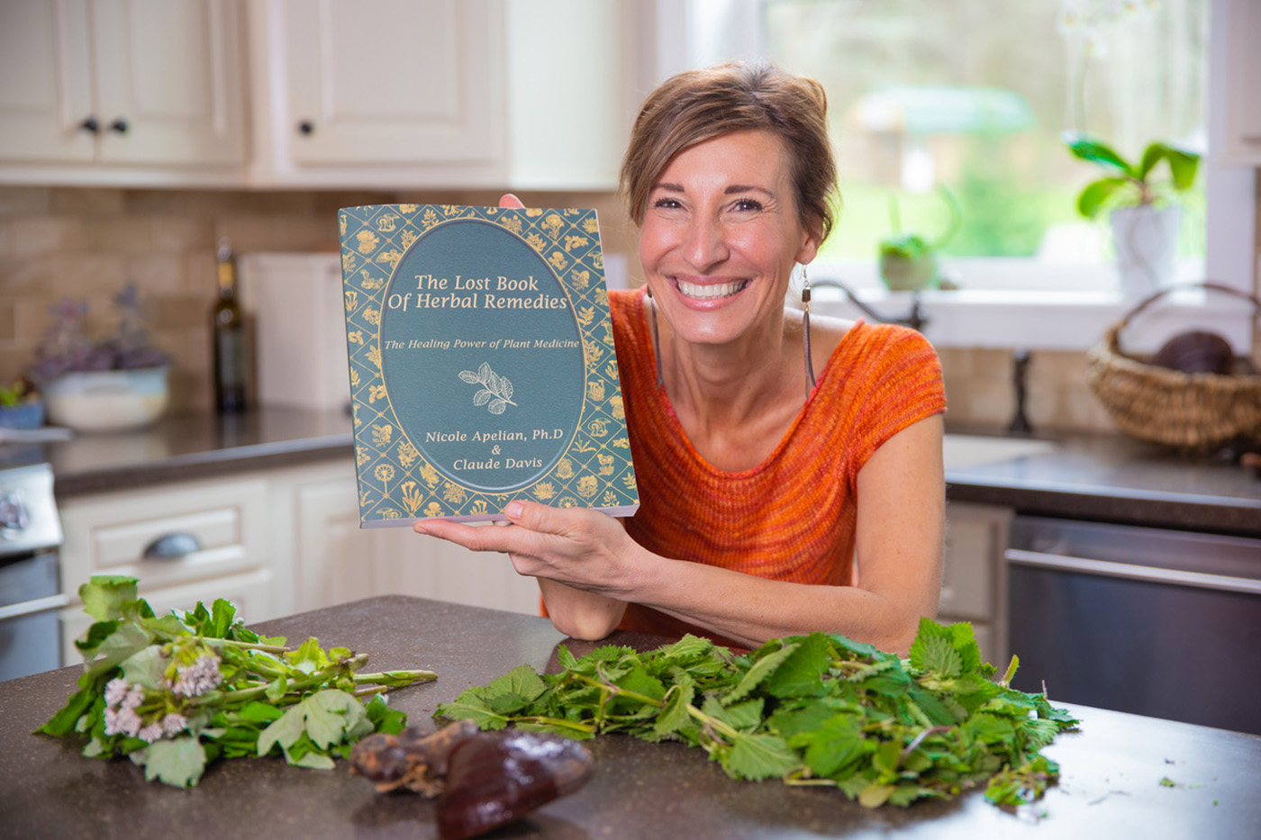 Nicole Apelian holding a copy of her book The Lost Book of Herbal Remedies