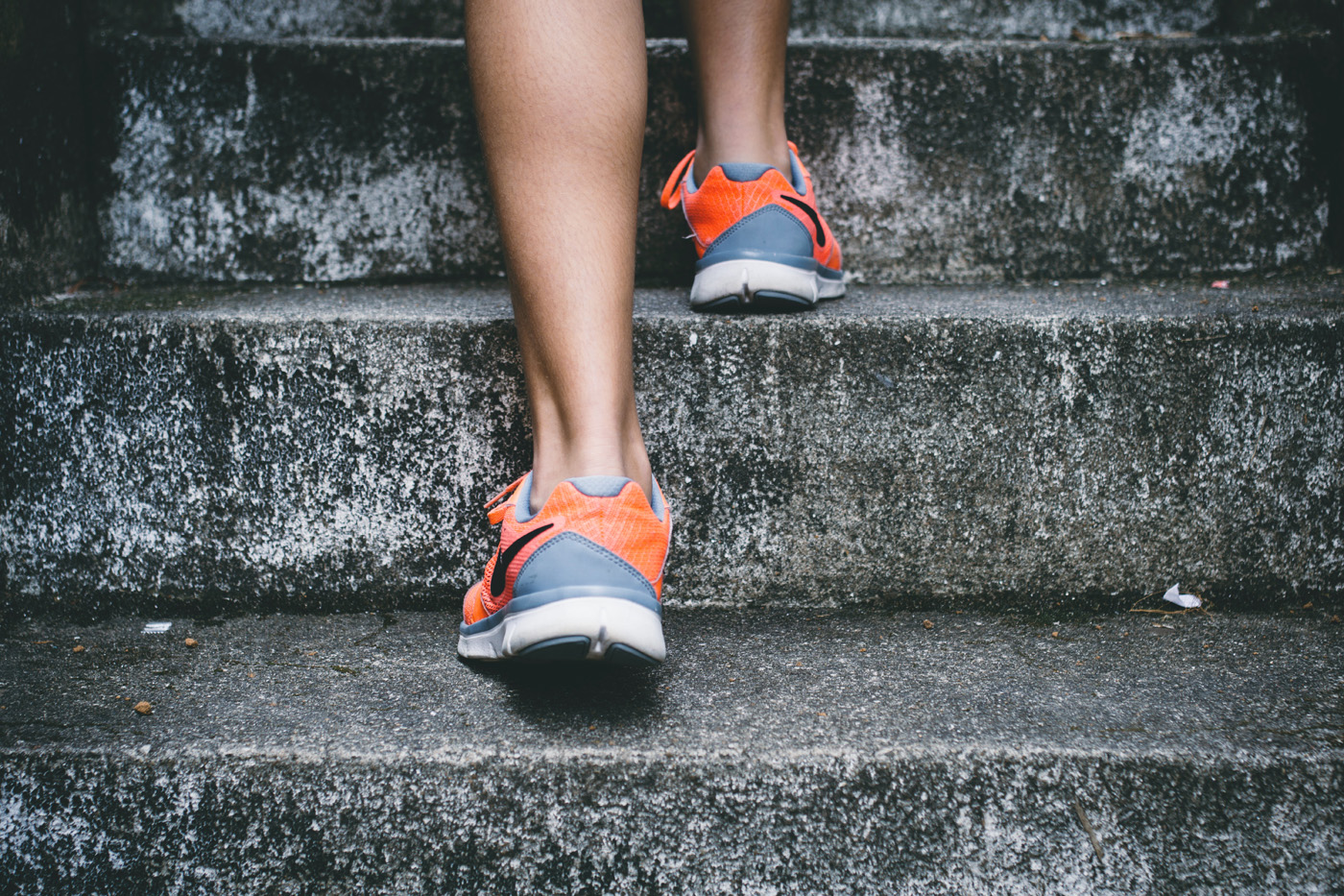 woman in running shoes stepping up stairs