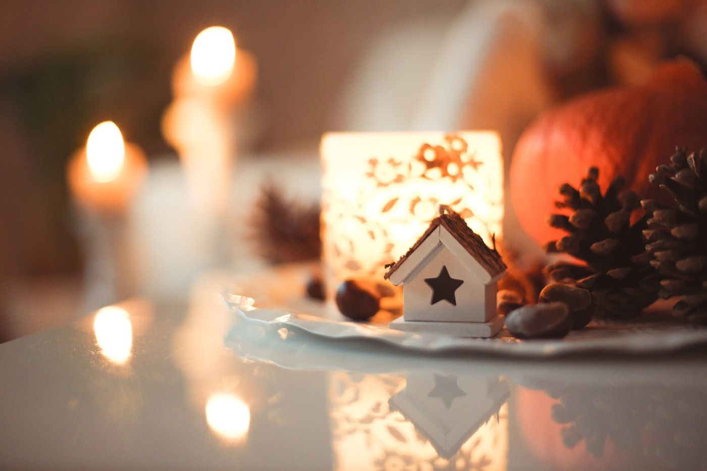 candlelight in autumn scene with pumpkin pine cones and house ornament