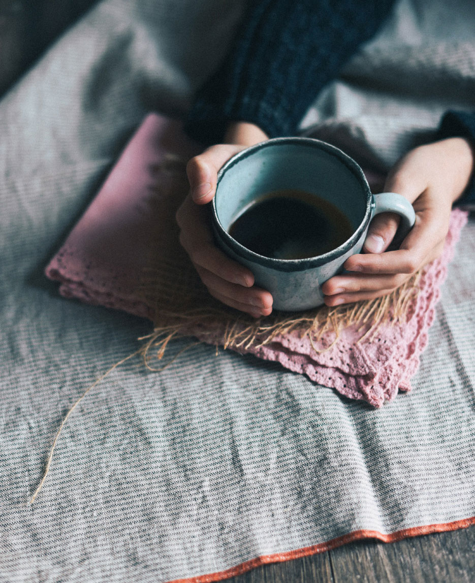 hand holding mug of tea on cozy table