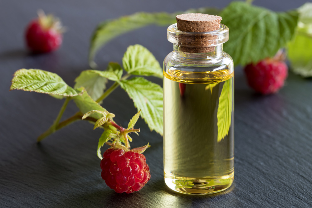 A bottle of raspberry seed oil with raspberries