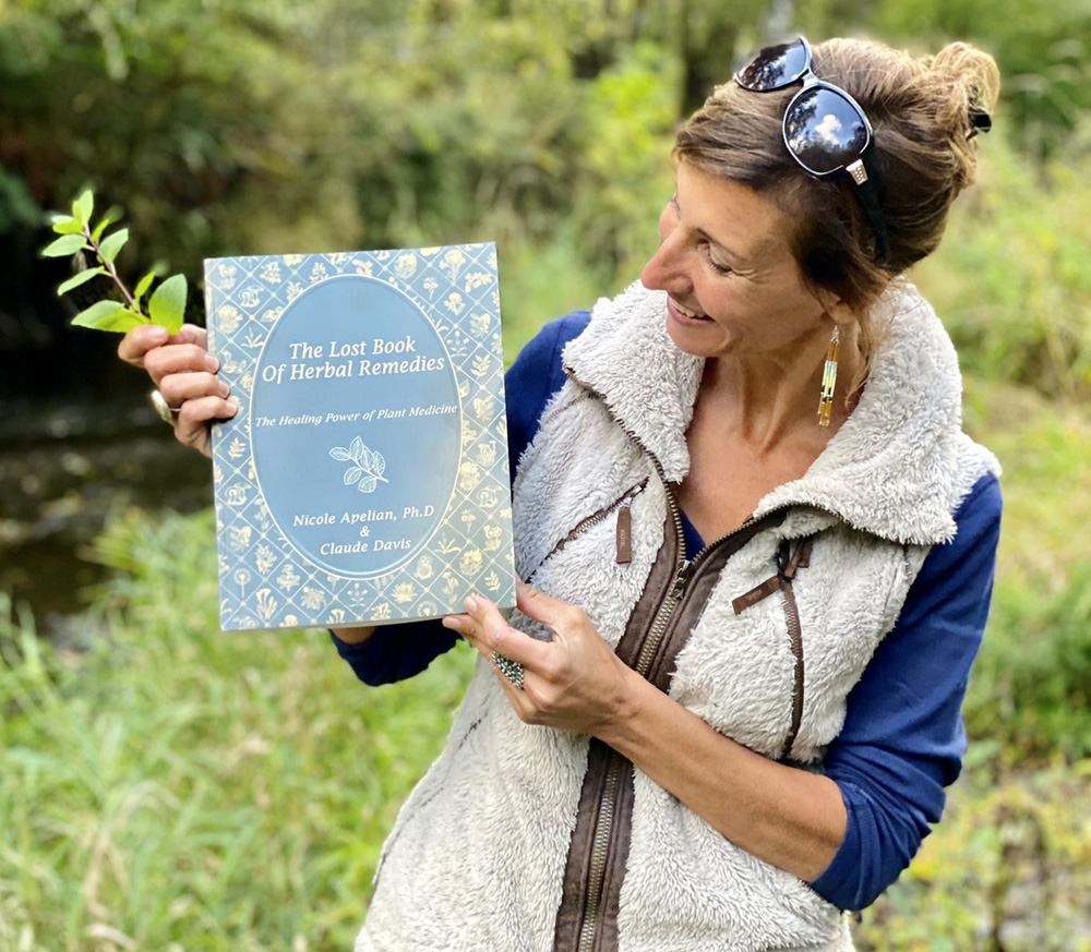 Nicole Apelian holding copy of The Lost Book of Herbal Remedies