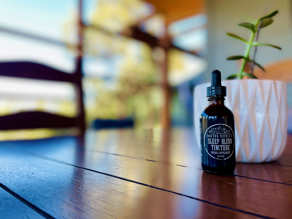 Nicoles Apothecary Sleep Blend Tincture on wood table next to window