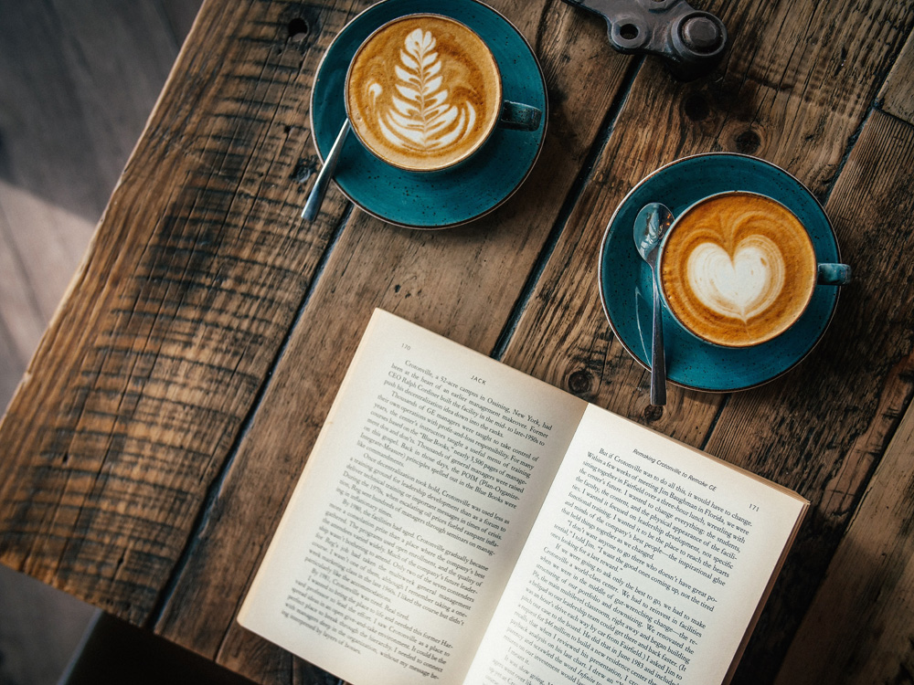 open book on table with coffees