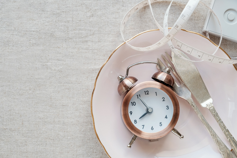 Intermittent fasting depicted by clock on plate and tape measure