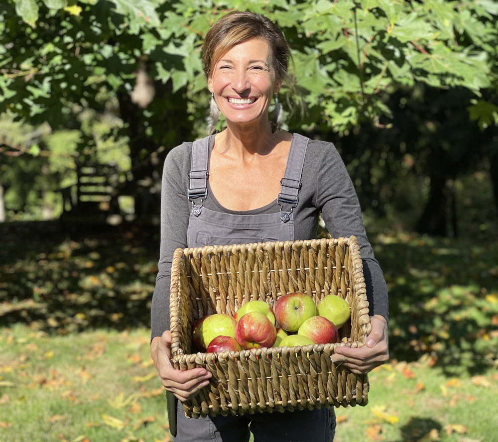 Nicole Apelian wearing Dovetail Workwear Freshly Overalls holding a basket of apples