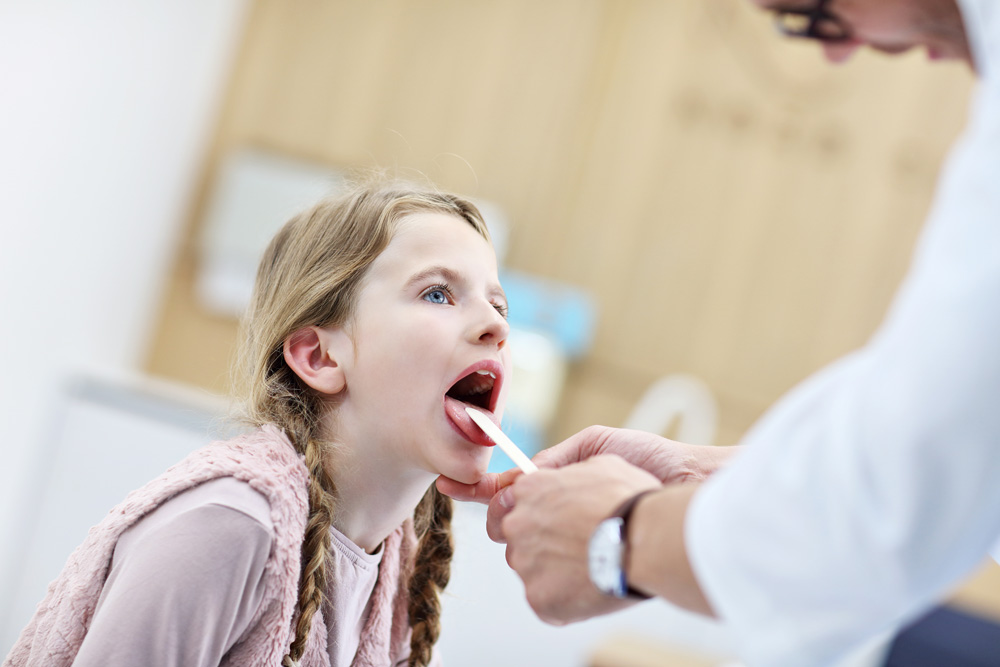 Little girl in clinic having a checkup with laryngologist