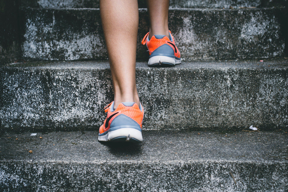 close up of womans feet in sneakers going upstairs