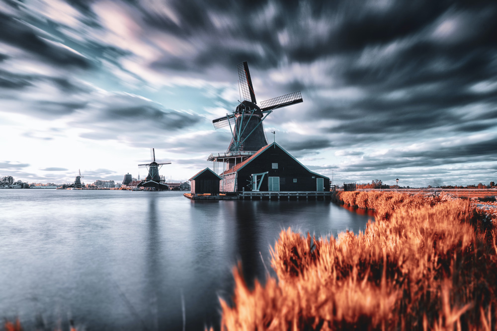 windmills on river with stormy sky