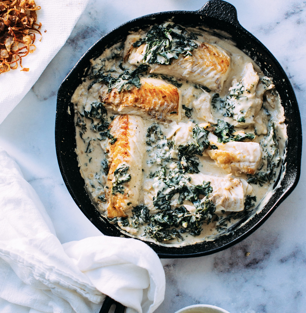 cast iron pan with fish spinach and cream sauce