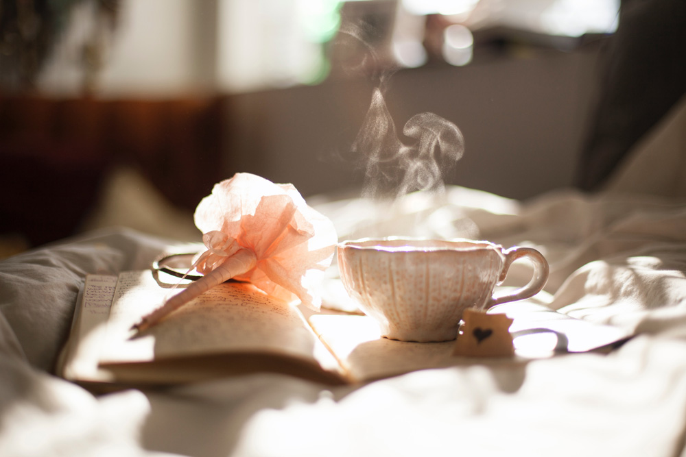 steaming cup of tea next to journal and pen