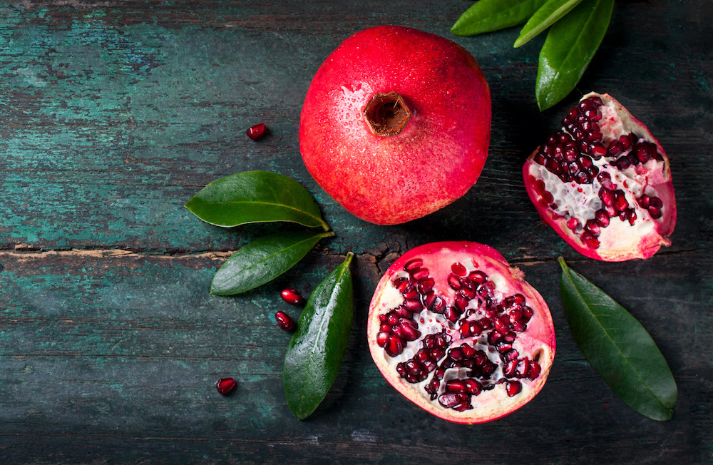 Pomegranate with leaves on wood background