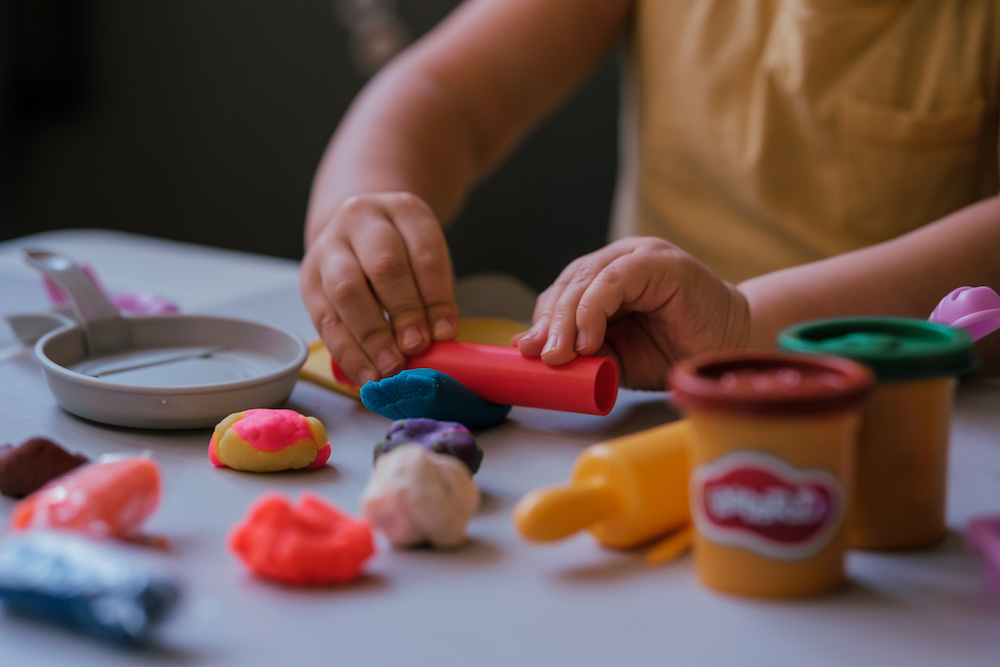 Toddler boy playing with play dough at home