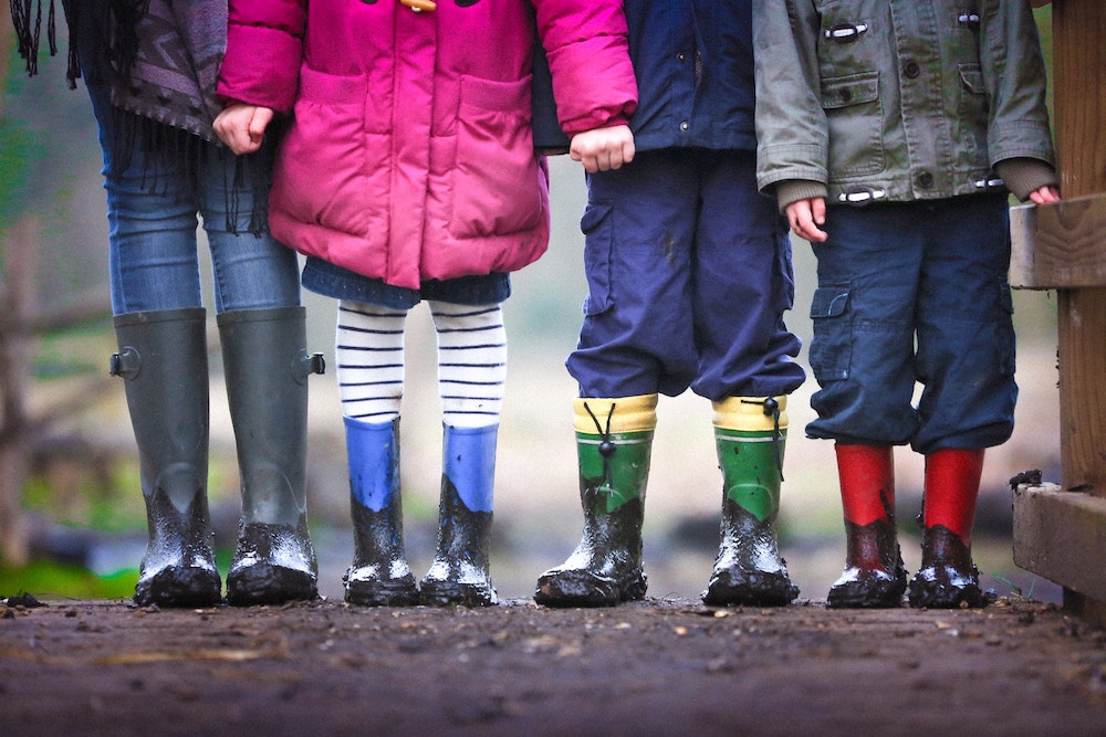 children bundled up and wearing rainboots outside