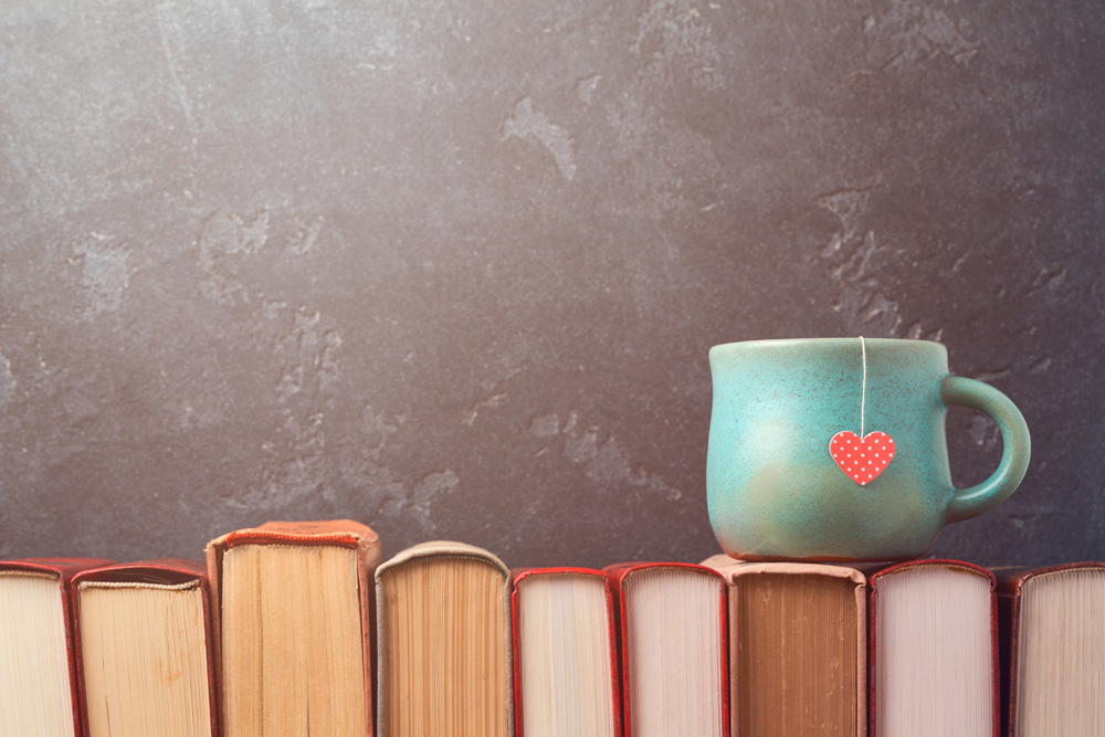 tea cup with heart on books over blackboard bac