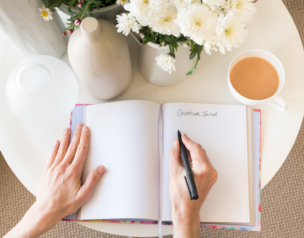 woman's hands writing in gratitude journal