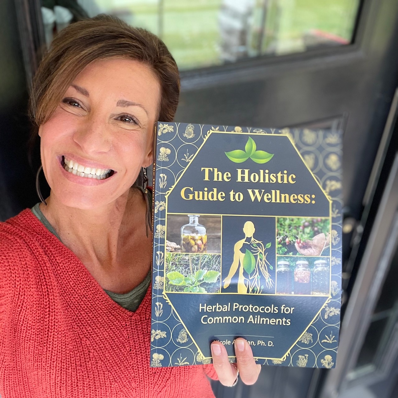 Nicole Apelian holding her Holistic Guide to Wellness book