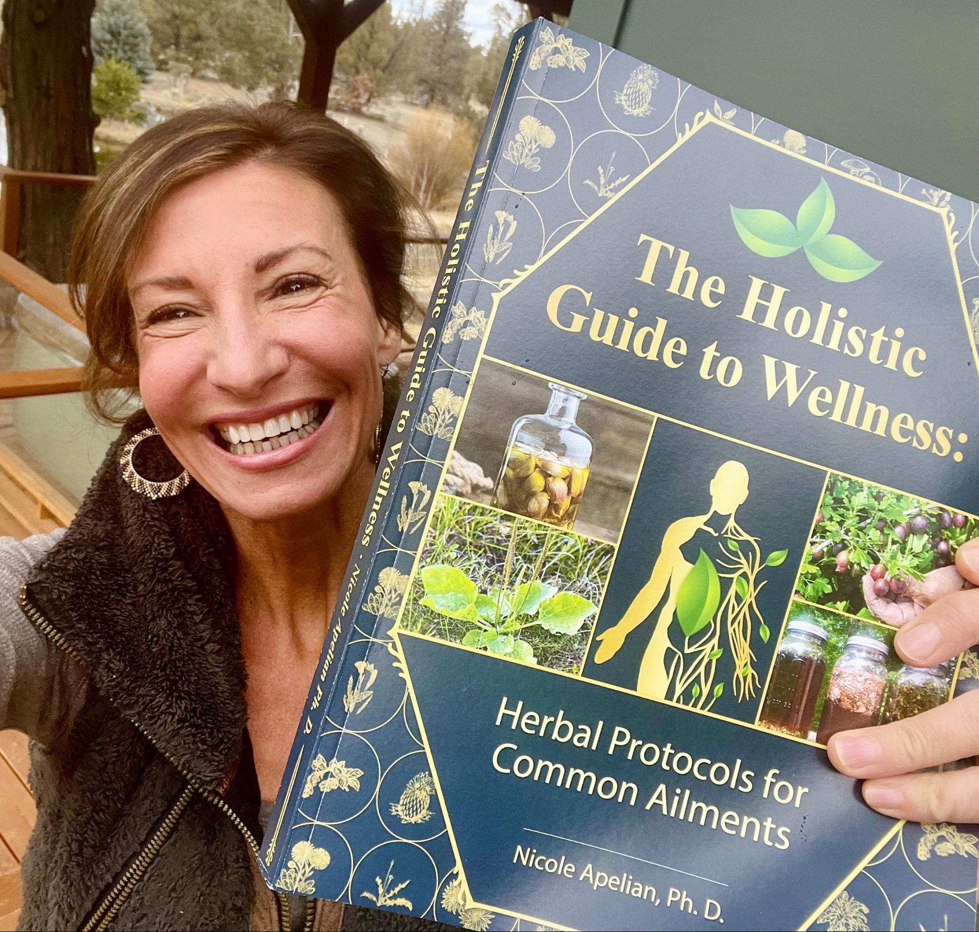Nicole Apelian holding her Holistic Guide to Wellness book