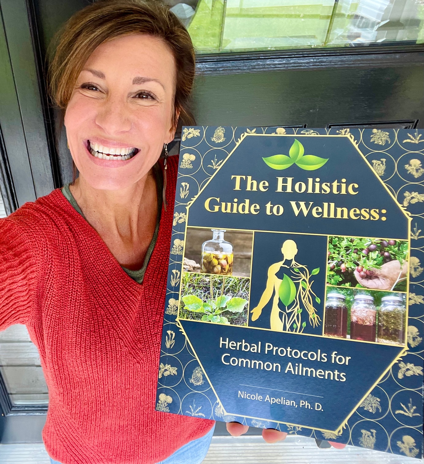 Nicole Apelian holding her Holistic Guide to Wellness book