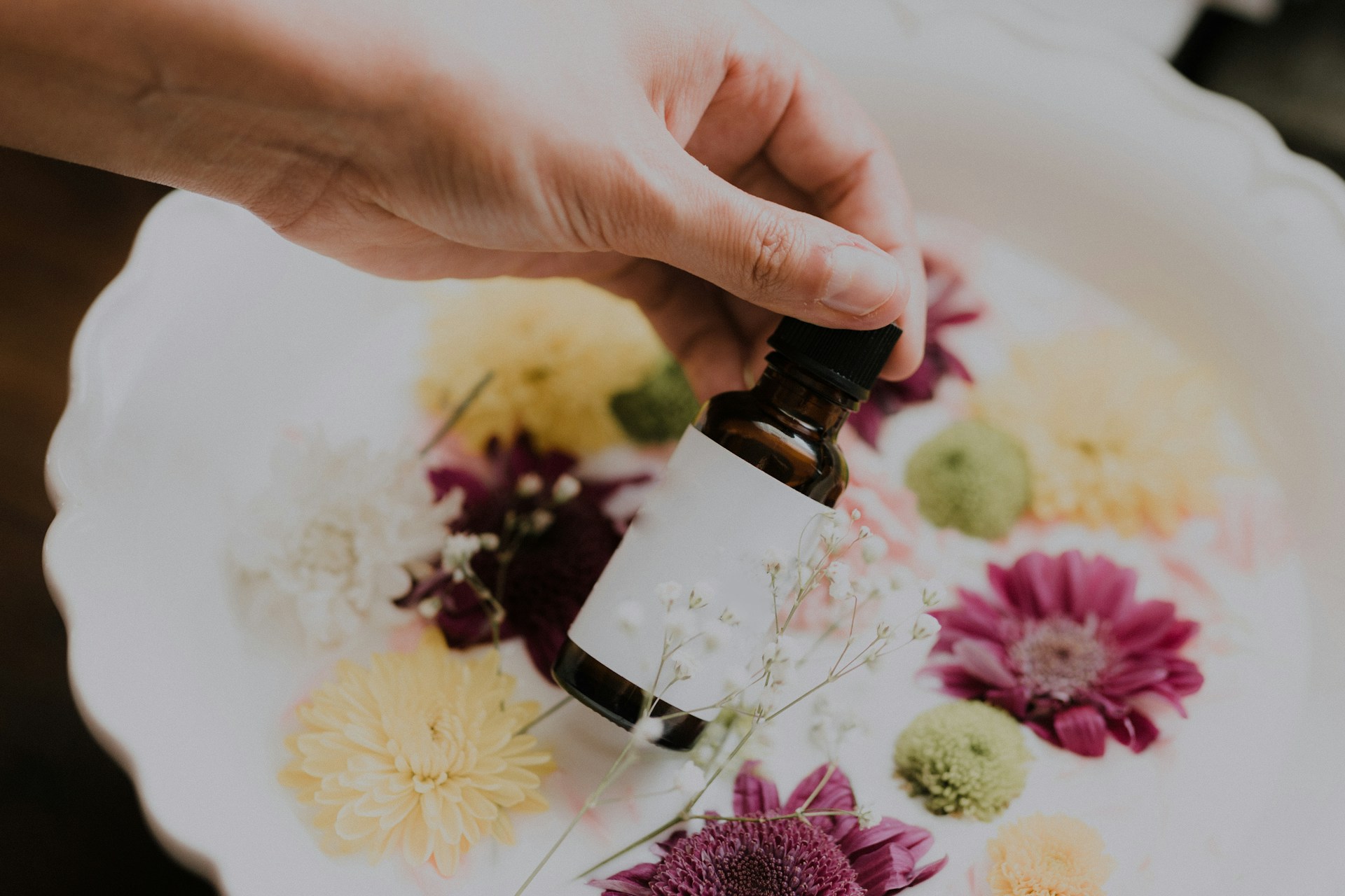 hand holding essential oil bottle over dryied florals