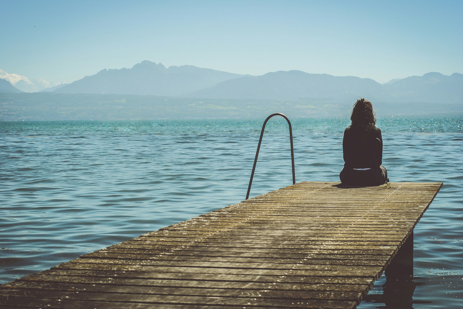 solitary woman sitting on dock
