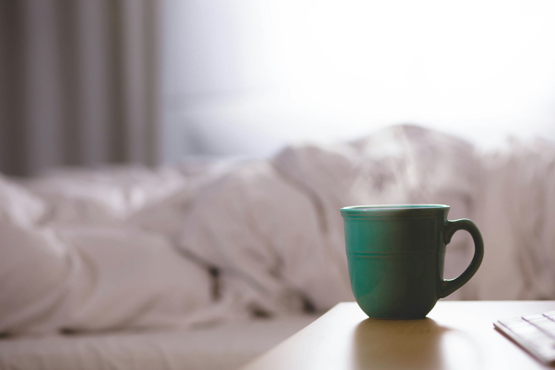 steaming green mug next to bed