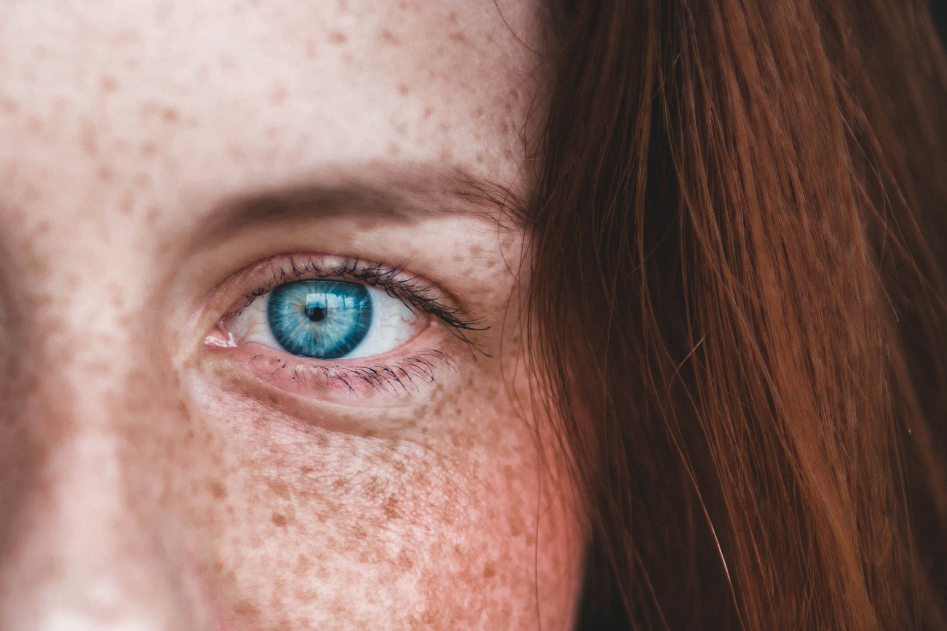  closeup of blue eye on woman with red hair and freckles